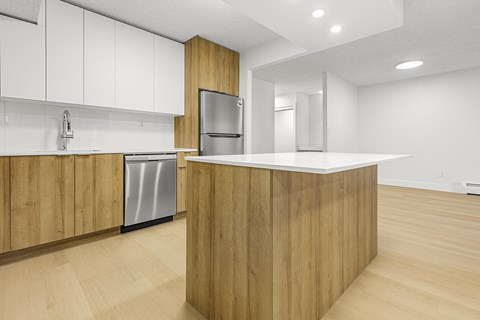 A modern kitchen with wooden cabinets and a stainless steel refrigerator.