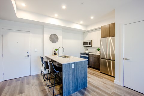 A kitchen with a white counter top and a stainless steel refrigerator.