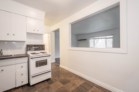 A kitchen with white cabinets and a tiled floor.