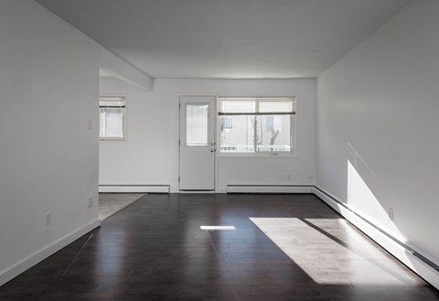A room with a white door and a window with white blinds.