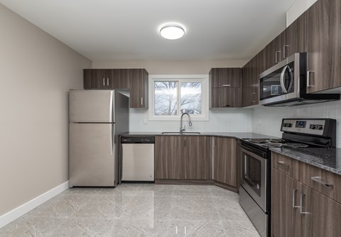 A kitchen with a refrigerator, microwave, and oven.