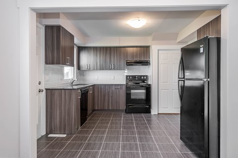 A kitchen with a black refrigerator and brown cabinets.