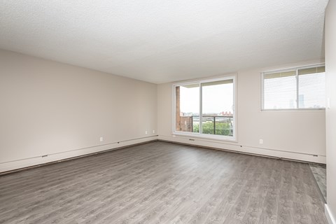 A spacious room with a large window and wooden flooring.