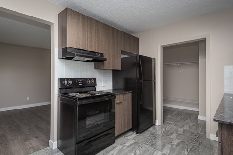 A kitchen with a black stove top oven and black refrigerator.