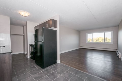 A black refrigerator is in the corner of a kitchen.