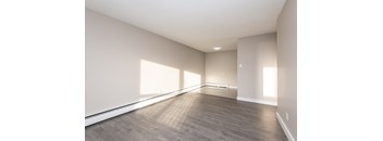 A large empty room with wooden flooring and white walls.