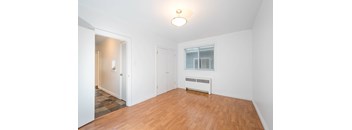 A room with a wooden floor and a window with blinds.
