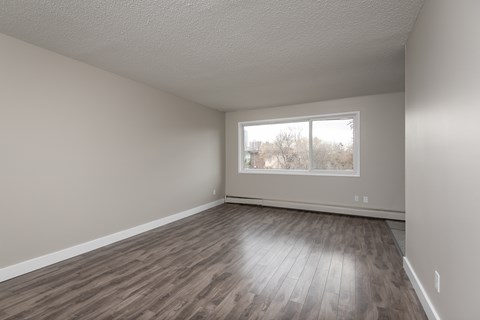 Empty room with wooden flooring and a window.