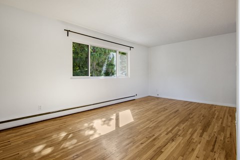 A room with wooden flooring and a window.