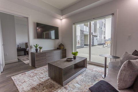 A modern living room with a large coffee table and a flat screen TV mounted on the wall.