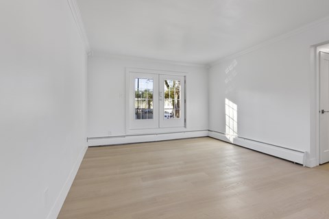 A room with a window and a wooden floor.