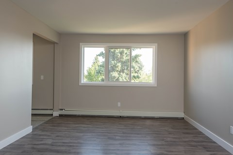 A room with a large window and wooden flooring.