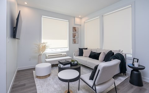 A living room with a white couch, a white ottoman, and a black chair.