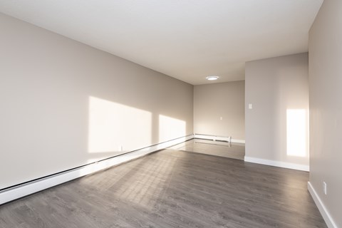 A large empty room with wooden flooring and white walls.