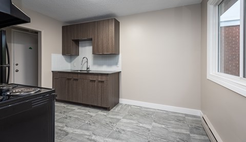 A kitchen with a black stove top oven and a brown cabinet.