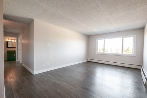 A spacious room with wooden flooring and a window.