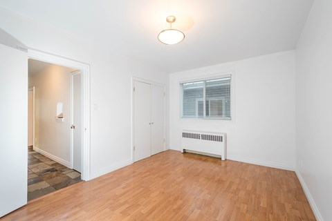 A room with a wooden floor and a window with blinds.