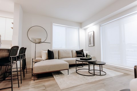 A modern living room with a white sofa, a black table, and a large window.