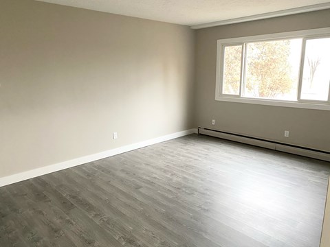 A room with a window and a grey floor.