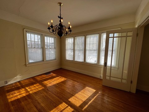 A room with a chandelier and wooden floors.