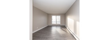 A spacious room with a window and wooden flooring.