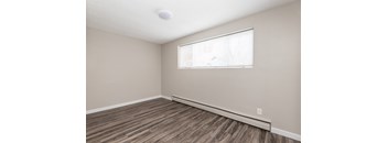 A room with a window and wooden flooring.