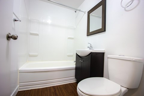 A white toilet sits next to a white bathtub in a bathroom.