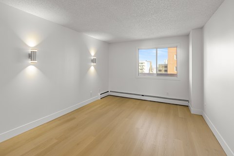A room with wooden floors and two wall lights.
