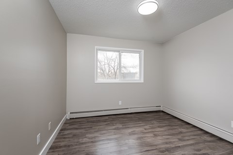 A room with a window and wooden flooring.