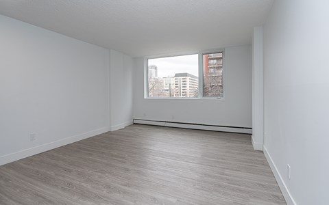Empty room with a window overlooking a cityscape.