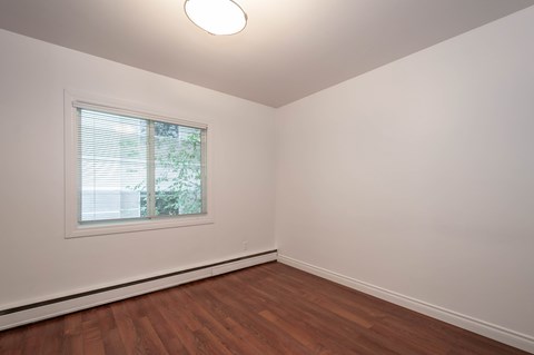 A room with a window and wooden flooring.
