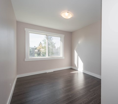 A room with a window and wooden flooring.