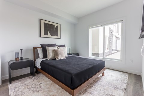 A bedroom with a large bed and a window overlooking a city street.