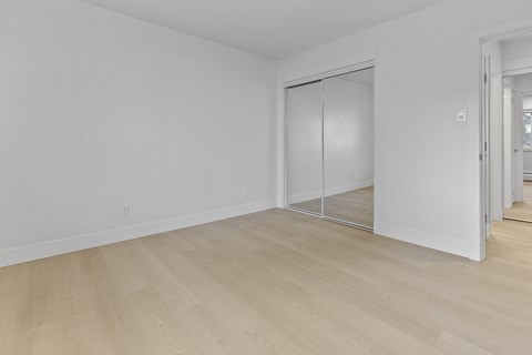 A room with a white wall and a white closet with a sliding door.