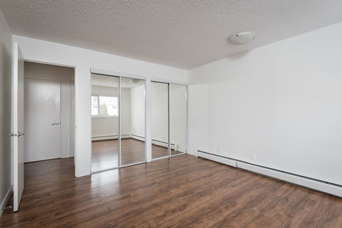 A room with white walls and wooden floors with a sliding glass door.