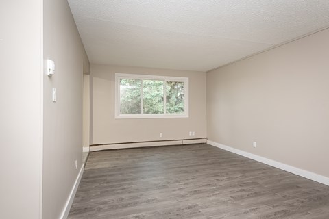 A room with a window and a wooden floor.