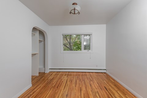 A room with a window and a wooden floor.