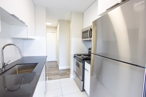 A modern kitchen with a stainless steel refrigerator and a black countertop.