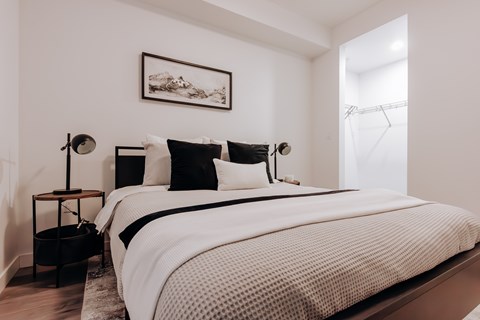 A bedroom with a large bed and a painting on the wall.