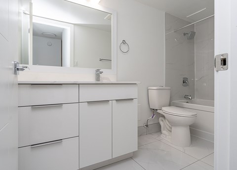 A white bathroom with a toilet, sink, and mirror.