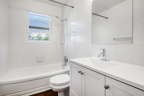 A white bathroom with a toilet, sink, and bathtub.