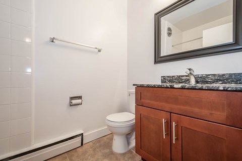 A bathroom with a toilet, sink, and a mirror.