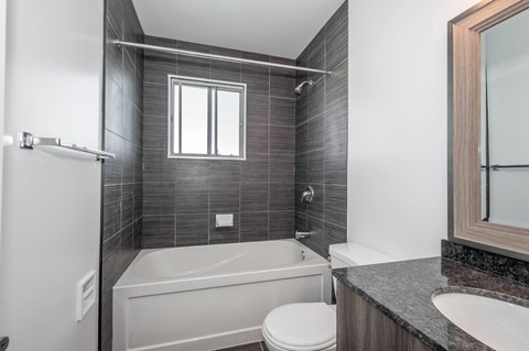 A modern bathroom with a white tub, toilet, and sink.