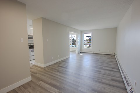 A spacious room with wooden flooring and white walls.