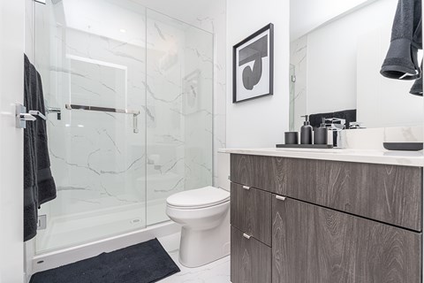 A bathroom with a toilet, sink, and a glass shower stall.