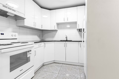 A white kitchen with a stove, oven, and cabinets.