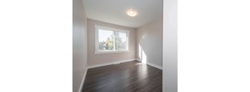 A room with a window and wooden flooring.