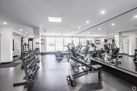 A gym with a variety of equipment including treadmills, weights, and exercise machines.
