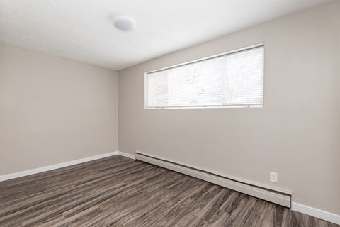 A room with a window and wooden flooring.