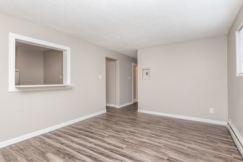 A room with wooden flooring and a window on the left side.